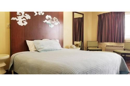 a bedroom with a bed with a white comforter at Century Motel Buena Park Anaheim CA 91 in Buena Park