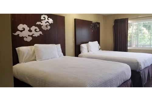 two beds in a hotel room with white sheets at Century Motel Buena Park Anaheim CA 91 in Buena Park