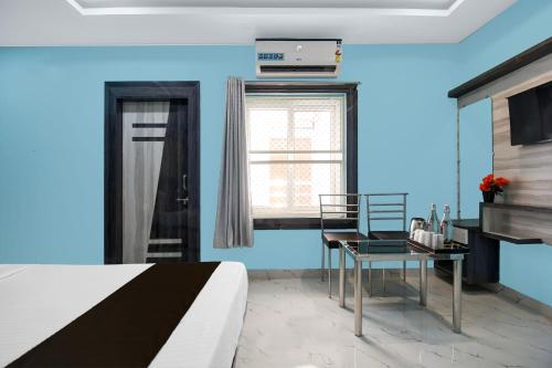 a blue room with a bed and a table and a window at Collection O Hotel Pearl Paradise in Puri