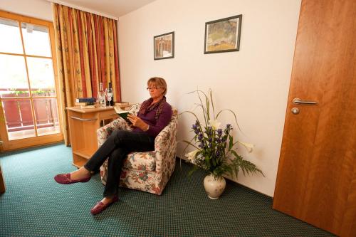 a woman sitting in a chair in a room at Familien- und Wellnesshotel "Viktoria" in Oberstdorf