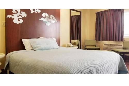 a bedroom with a bed with a white comforter at Century Motel Buena Park Anaheim CA 91 in Buena Park