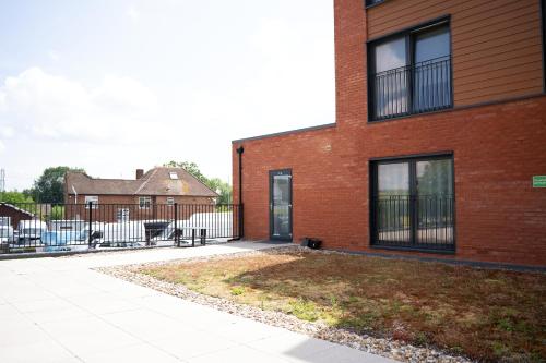 a red brick building with a yard in front of it at Modern 1-Bedroom Apartment with Parking near Heathrow in Colnbrook