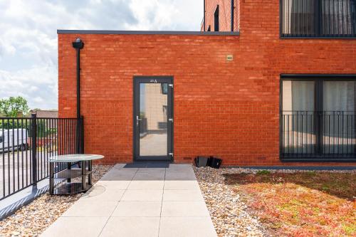 a red brick building with a door and a bench at Modern 1-Bedroom Apartment with Parking near Heathrow in Colnbrook