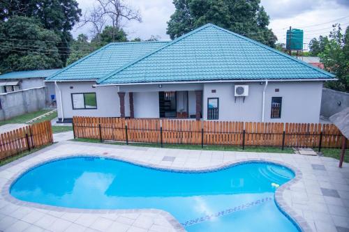 a house with a blue pool in front of a fence at La Consolata Villa Olympia Extension in Lusaka