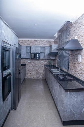 a large kitchen with stainless steel appliances and brick walls at La Consolata Villa Olympia Extension in Lusaka