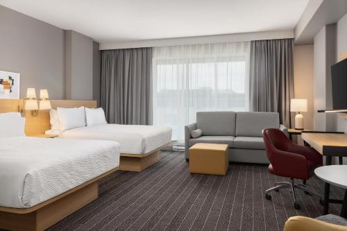 a hotel room with two beds and a couch at Staybridge Suites Montreal Airport - St-Laurent by IHG in Montréal