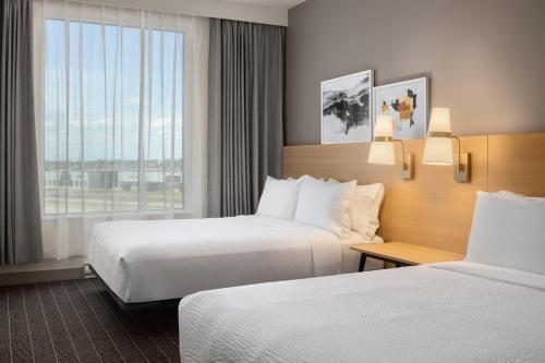 a hotel room with two beds and a window at Staybridge Suites Montreal Airport - St-Laurent by IHG in Montréal