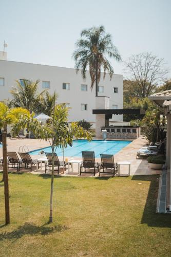 a swimming pool with chairs and a building at Valinhos Plaza Hotel in Valinhos