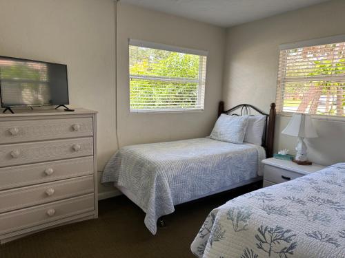 a bedroom with two beds and a dresser and two windows at Tropical Villas Of Venice Beach in Venice