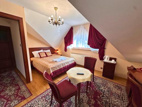 a bedroom with a bed and a table and chairs at Pensjonat Szach in Krynica Zdrój