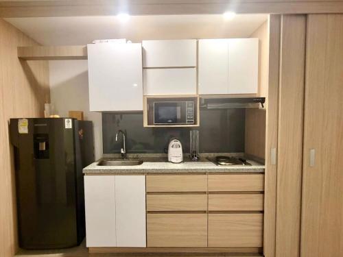 a kitchen with white cabinets and a black refrigerator at Belmonte Studios perfect location with pool cowork and amazing view in Armenia