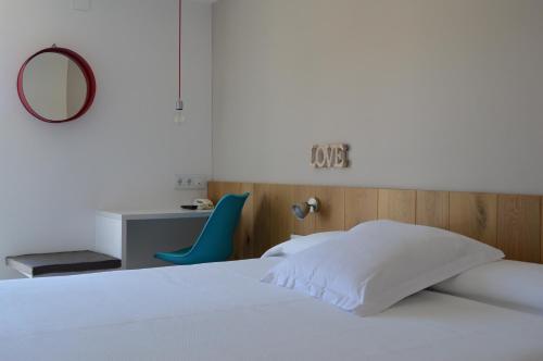 a bedroom with a bed and a desk and a mirror at Hotel Nou Estrelles in Cadaqués