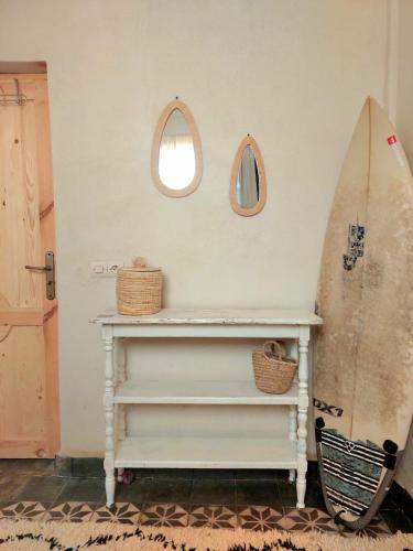 a room with a table and a surfboard on the wall at Moroccan Boho Surf House in Agadir