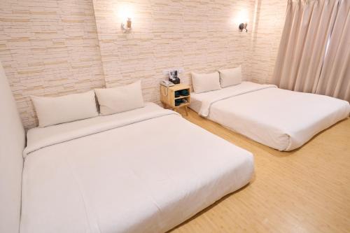 two beds in a room with white sheets at The Riverside Hotel Fashion in Kaohsiung
