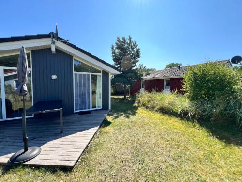 a house with a wooden porch with an umbrella at Strandhaus Dünenpark 1c in Priwall