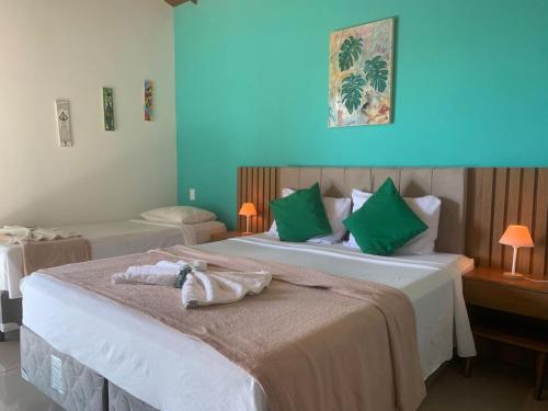 a hotel room with two beds with green pillows at Foca Guest House in Búzios