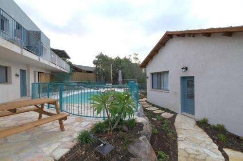 a patio with a bench next to a building at חווייה של שקט- מתחם שלם עם בריכה- רק בשבילכם in Livnim