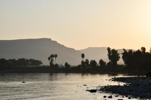 a river with trees and a mountain in the background at חווייה של שקט- מתחם שלם עם בריכה- רק בשבילכם in Livnim