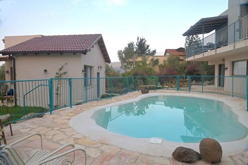 a swimming pool in a yard next to a house at חווייה של שקט- מתחם שלם עם בריכה- רק בשבילכם in Livnim