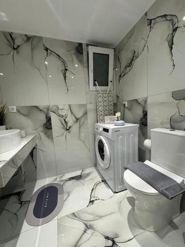 a bathroom with a toilet and a washing machine at George luxury stone apartment in Vonitsa