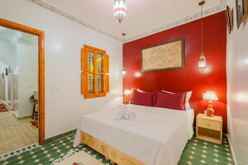 a bedroom with a white bed and a red wall at Riad Dar Z'r in Marrakech