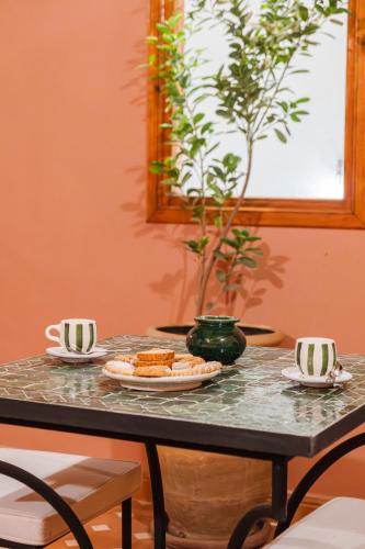 a table with a plate of food and two cups at Riad Dar Z'r in Marrakech
