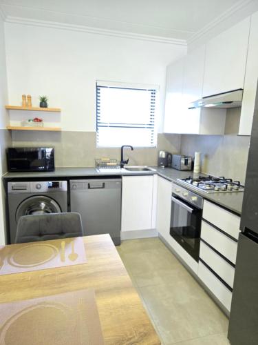 a kitchen with white cabinets and a table in it at The One One Two in Sandton