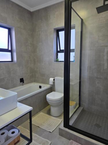 a bathroom with a tub and a toilet and a sink at The One One Two in Sandton