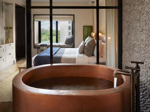 a bathroom with a bath tub in front of a bed at 1 Hotel Central Park in New York