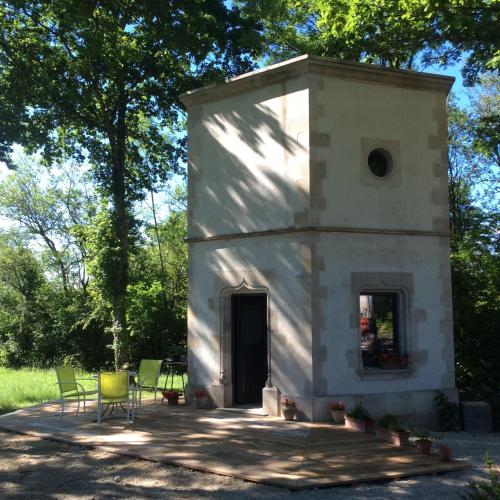 a small white building with chairs in front of it at Hexagonal Tower for 2 with shared pool in Semur-en-Auxois