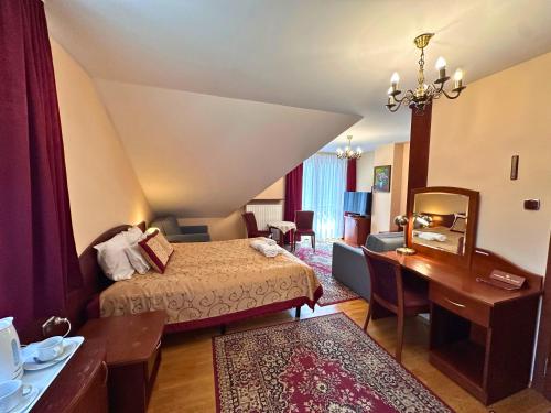a hotel room with a bed and a desk at Pensjonat Szach in Krynica Zdrój