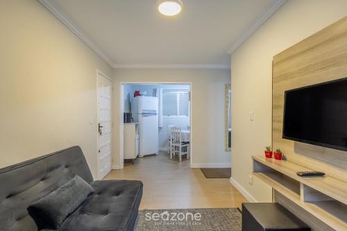 Una sala de estar con un sofá y un televisor de pantalla plana. en Apto funcional a 120m de la playa en BC | CEC0302, en Balneário Camboriú