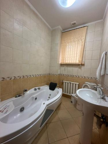 a bathroom with a tub and a toilet and a sink at Гостевой дом Ласточка 2 in Almaty