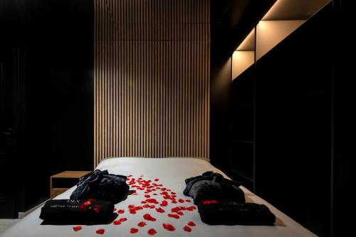 a bed with red petals on it in a room at Obsidian Luxury Suite - balnéo, miroirs aux plafonds, proche disney in Montévrain
