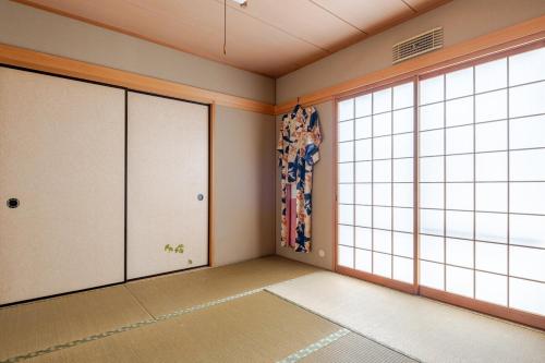 an empty room with large windows in a room at グループ宿泊に最適 Spacious Home Base by Yadoya in Yokkaichi