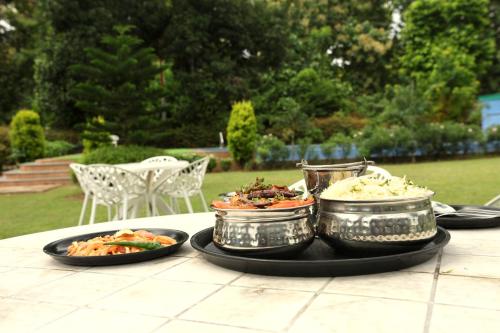 a table with three dishes of food on it at Aranya Resort & Suites By Shivaneel Hospitality in Rāmnagar