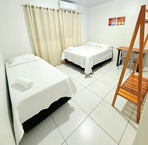 a room with two beds and a wooden chair at Ap conforto no centro de Sinop 2 in Sinop