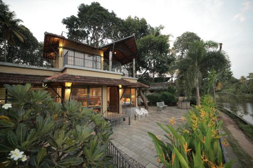 a house with a balcony and a river at Ripples Cove Retreat - Your dream Lakeside getaway in Paravūr