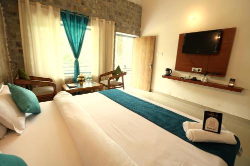 a bedroom with a large bed with a tv on the wall at Aranya Resort & Suites By Shivaneel Hospitality in Rāmnagar