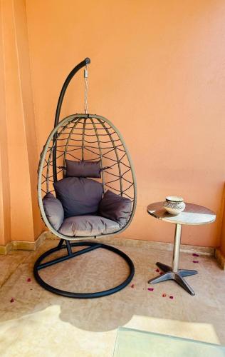 a chair with pillows in a room with a table at Kridarek - Magnifique Villa avec piscine à Marrakech in Douar bel Rhanodour