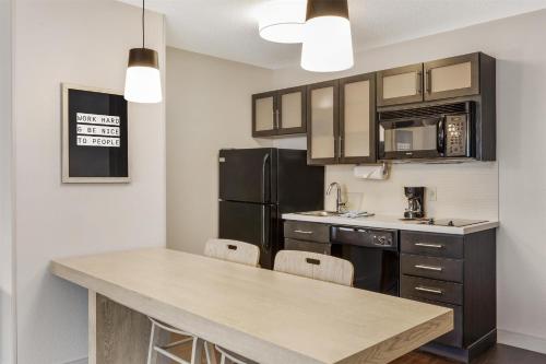 a kitchen with a table and a black refrigerator at Sonesta Simply Suites Boston Burlington in Burlington