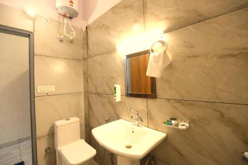 a bathroom with a sink and a toilet and a mirror at Aranya Resort & Suites By Shivaneel Hospitality in Rāmnagar