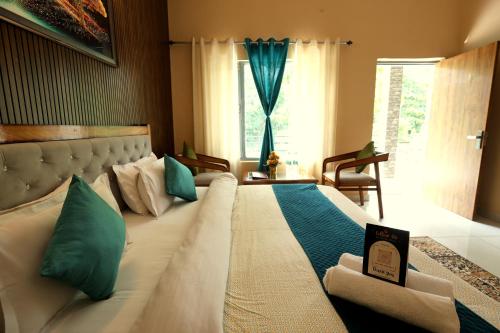 a large white bed in a room with a window at Aranya Resort & Suites By Shivaneel Hospitality in Rāmnagar