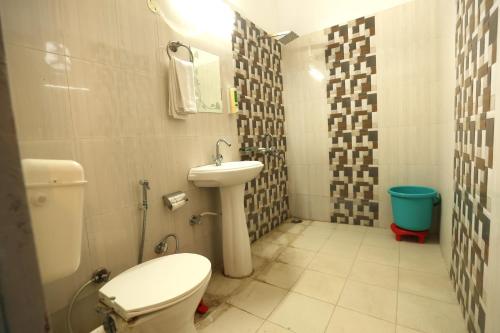 a small bathroom with a toilet and a sink at Aranya Resort & Suites By Shivaneel Hospitality in Rāmnagar