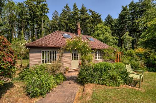 a small house with a bench in a yard at Tranquil Woodland Cottage, 10-Min Drive to Clifton in Pill