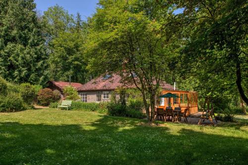 a house with a table and chairs in a yard at Tranquil Woodland Cottage, 10-Min Drive to Clifton in Pill