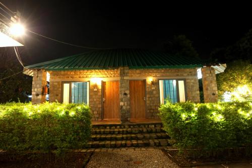 a small house with a green roof and a door at Aranya Resort & Suites By Shivaneel Hospitality in Rāmnagar