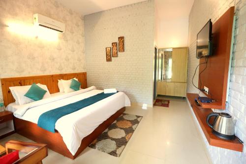 a bedroom with a large bed and a television at Aranya Resort & Suites By Shivaneel Hospitality in Rāmnagar