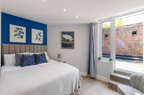 a bedroom with a bed with blue walls and a window at Perfect Flat Next To Highgate Station in London