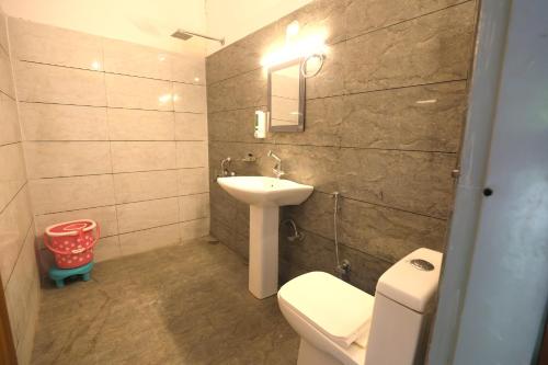 a small bathroom with a sink and a toilet at Aranya Resort & Suites By Shivaneel Hospitality in Rāmnagar